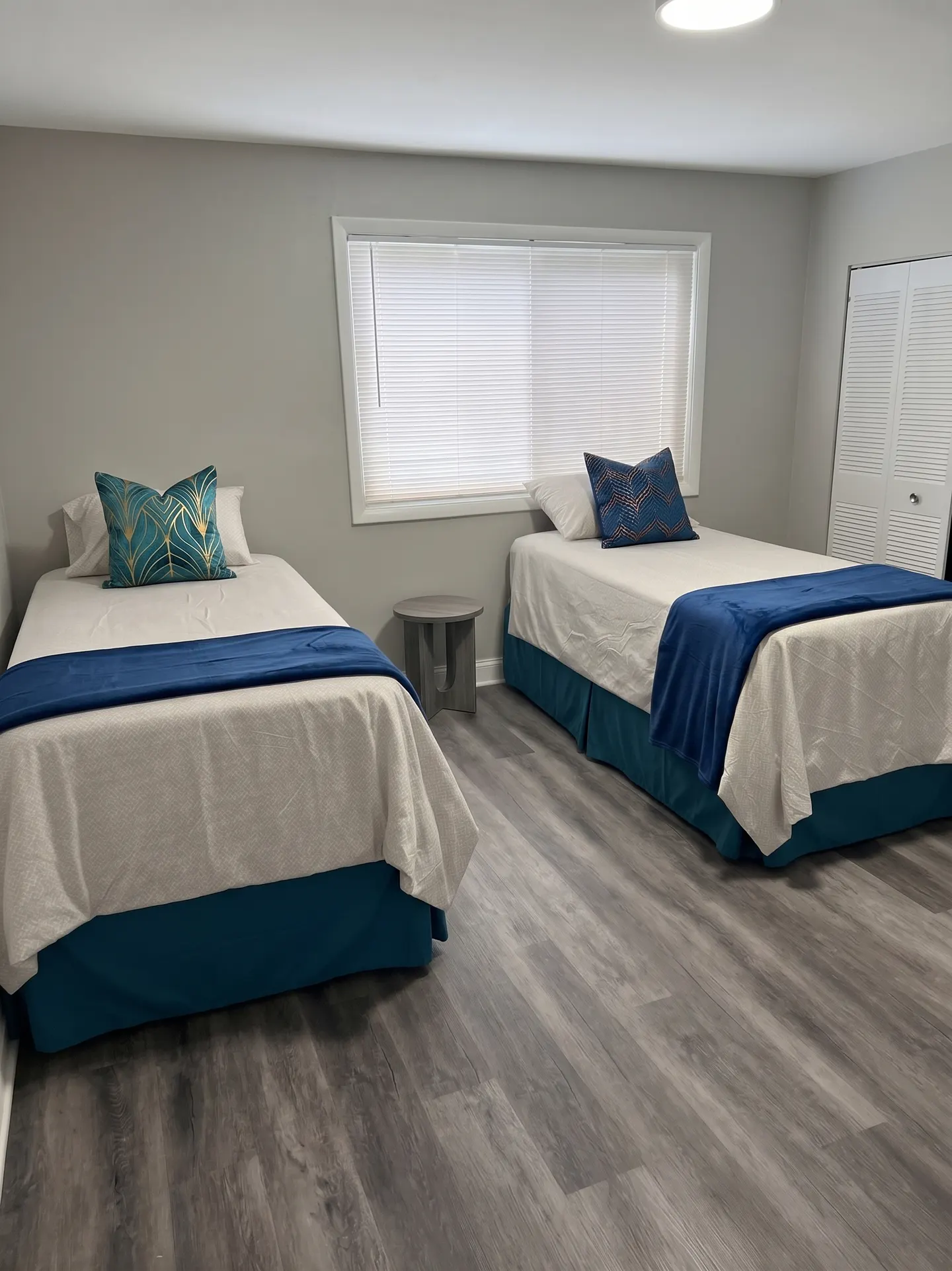 Furnished bedroom with two twin beds, navy and teal bedding, and a nightstand