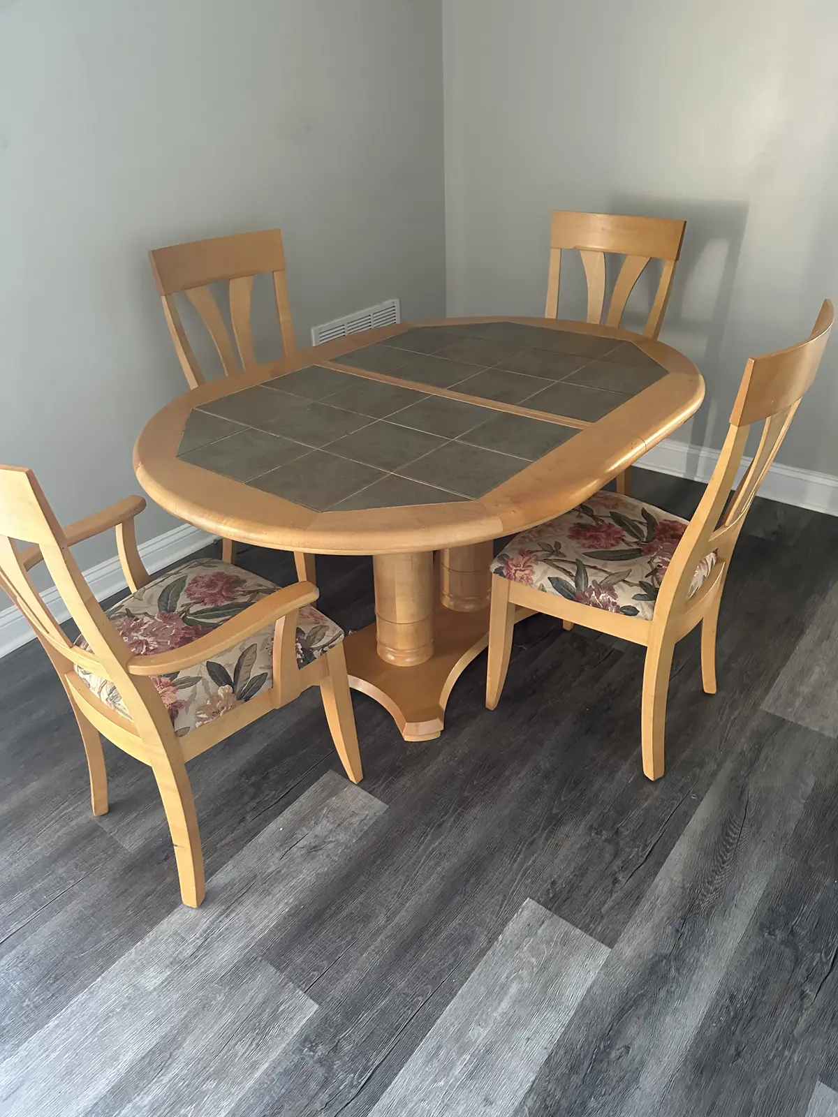 Dinette set with an oval tile-top table and four cushioned chairs on new flooring