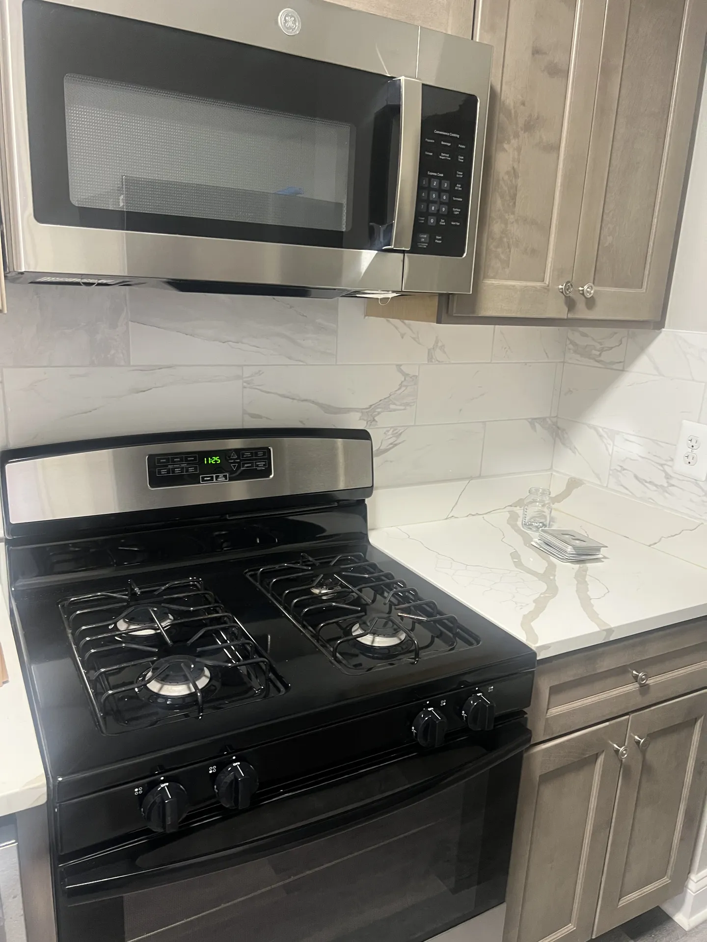 Kitchen with a gas range, over-the-range microwave, and marble-look backsplash and countertop