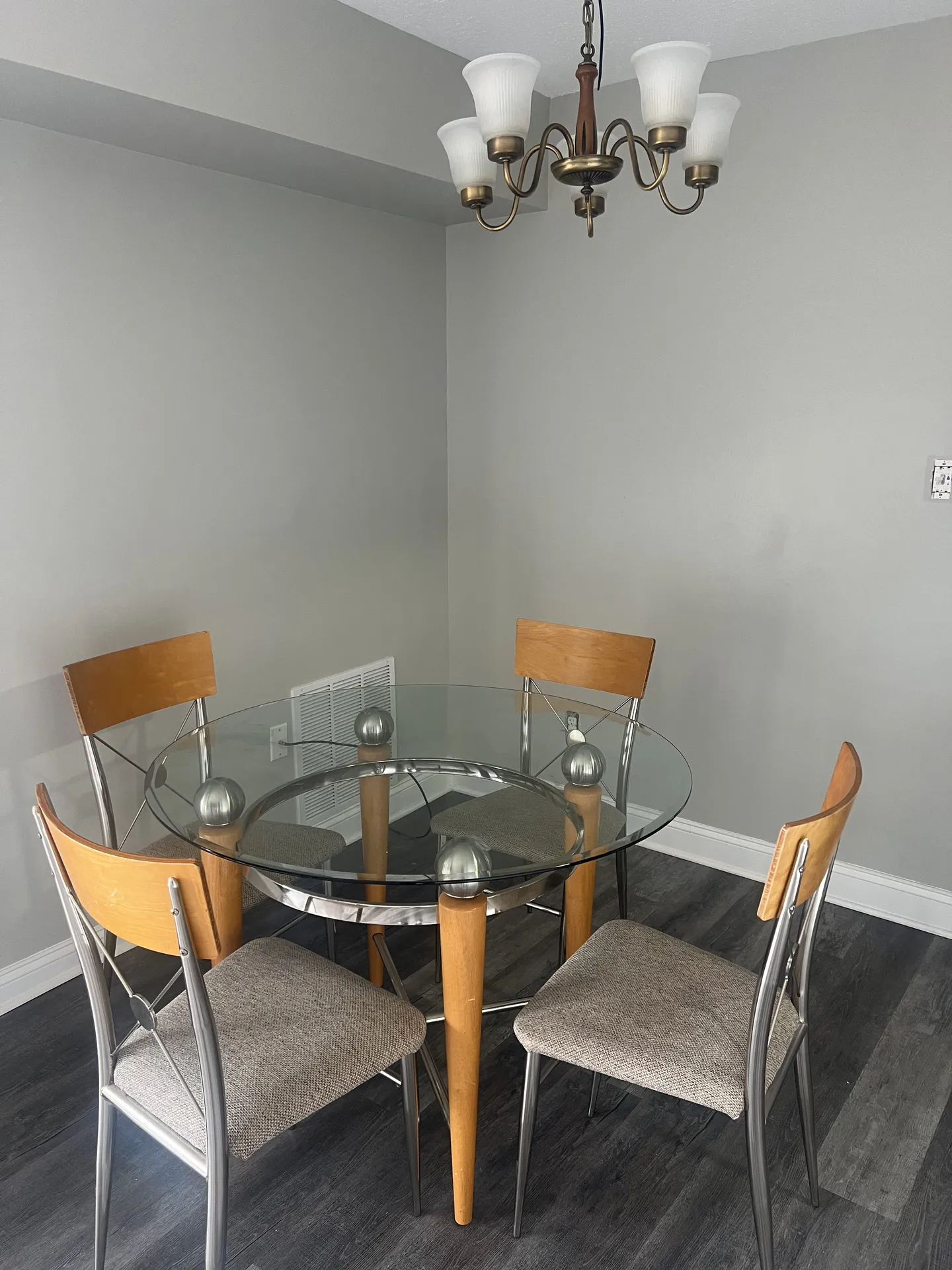 Furnished dining area with a round glass table, four chairs, and a chandelier